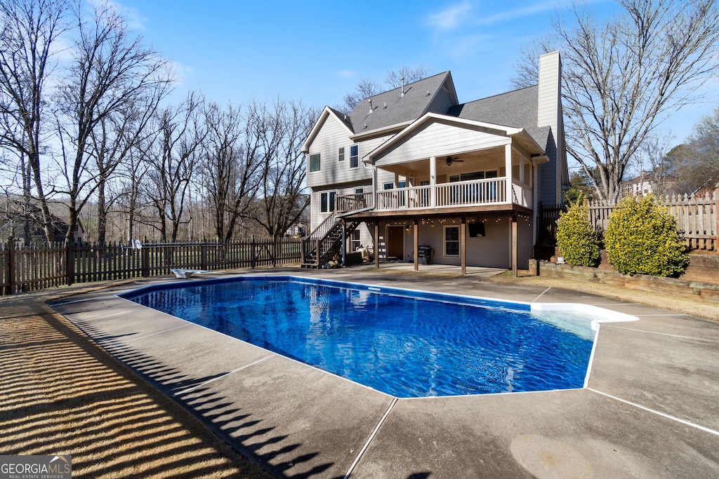 view of swimming pool with a patio, a diving board, and ceiling fan