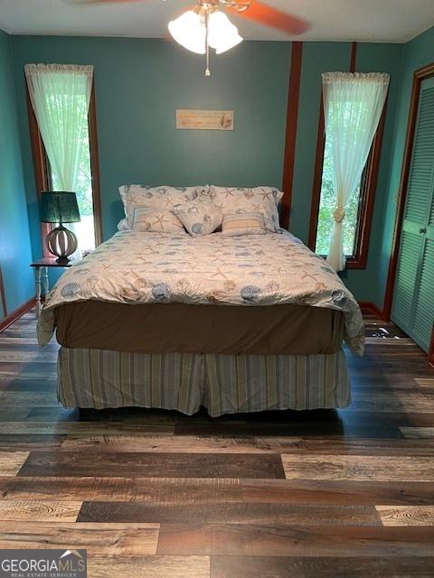 bedroom with dark wood-type flooring, ceiling fan, and multiple windows