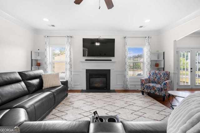 living room with crown molding, a wealth of natural light, french doors, and light wood-type flooring