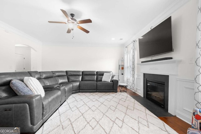 living room with crown molding, dark wood-type flooring, and ceiling fan