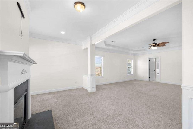 unfurnished living room with ornate columns, ornamental molding, light colored carpet, ceiling fan, and a tray ceiling