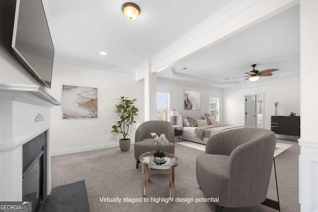 carpeted living room featuring ceiling fan, ornamental molding, and a raised ceiling