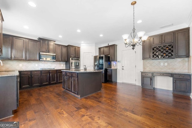 kitchen featuring pendant lighting, stainless steel appliances, a center island, and dark brown cabinets