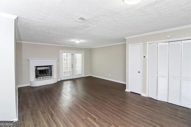 unfurnished living room with ornamental molding, a brick fireplace, a textured ceiling, and dark hardwood / wood-style flooring