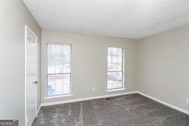 unfurnished room with a textured ceiling and dark colored carpet