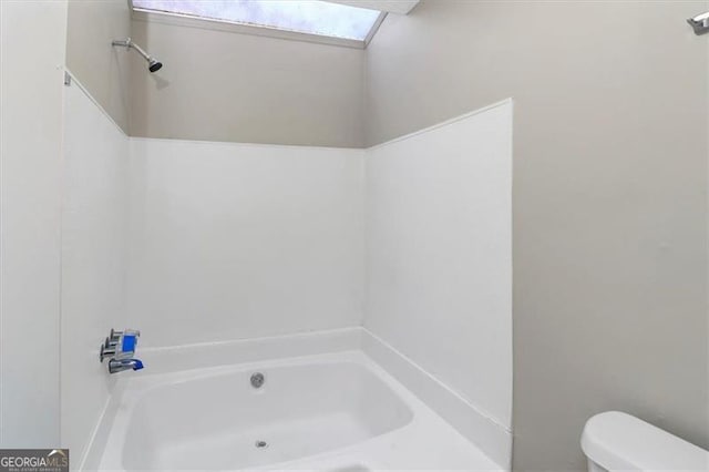 bathroom featuring a skylight, a tub, and toilet