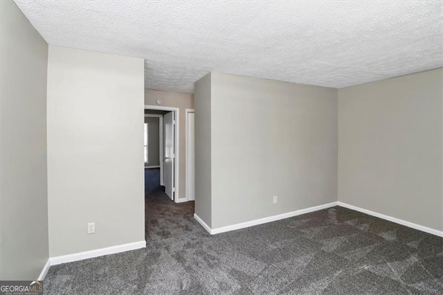 unfurnished room featuring dark carpet and a textured ceiling