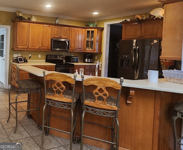 kitchen featuring crown molding, light tile patterned flooring, a kitchen breakfast bar, and appliances with stainless steel finishes