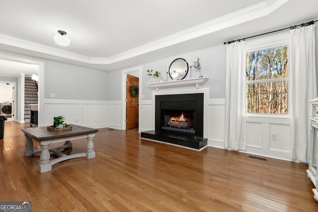 living room featuring washer / clothes dryer, crown molding, and wood-type flooring