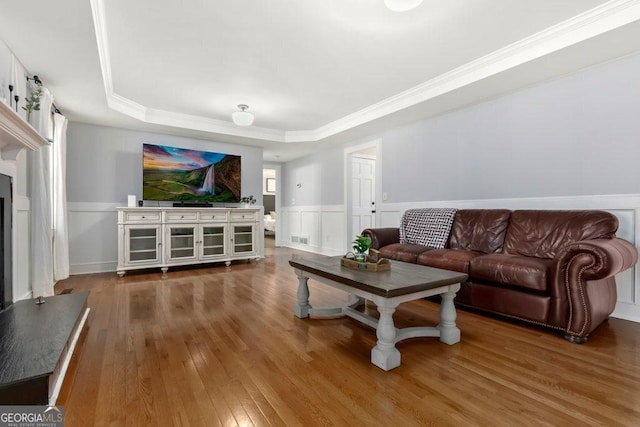 living room featuring a raised ceiling, ornamental molding, dark wood-type flooring, and a fireplace