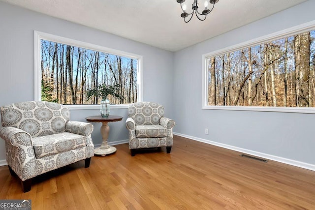 sitting room with a healthy amount of sunlight, a chandelier, and light wood-type flooring