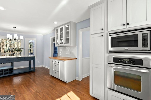 kitchen featuring dark wood-type flooring, wooden counters, white cabinetry, stainless steel appliances, and decorative light fixtures