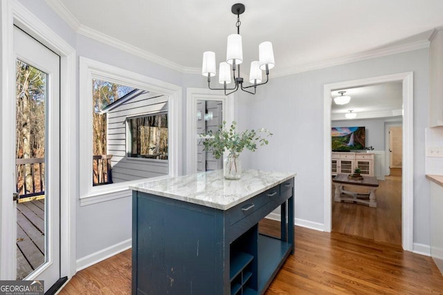 kitchen featuring crown molding, hanging light fixtures, blue cabinets, wood-type flooring, and a kitchen island