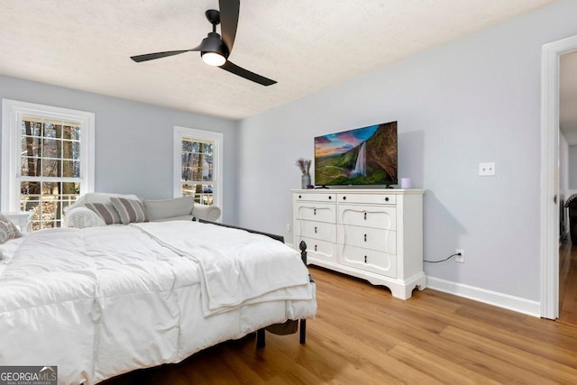 bedroom with ceiling fan, a textured ceiling, and light hardwood / wood-style floors