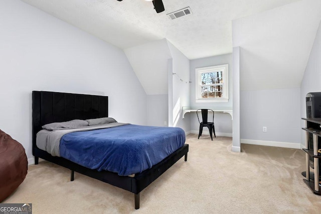 bedroom featuring lofted ceiling, a textured ceiling, light carpet, and ceiling fan