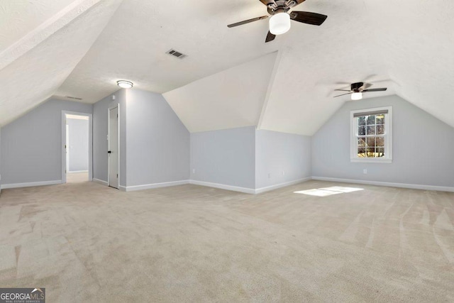 bonus room featuring lofted ceiling, light colored carpet, and a textured ceiling