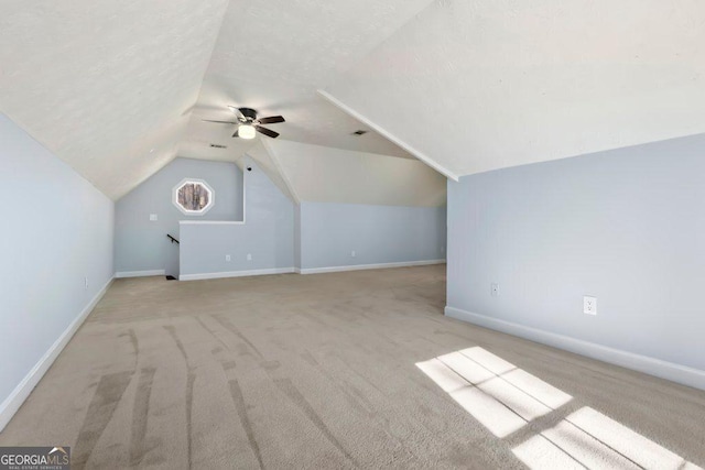 additional living space with lofted ceiling, ceiling fan, light colored carpet, and a textured ceiling