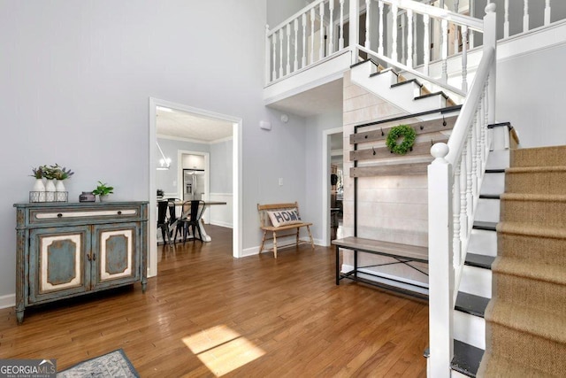 entrance foyer with crown molding, a towering ceiling, and hardwood / wood-style floors