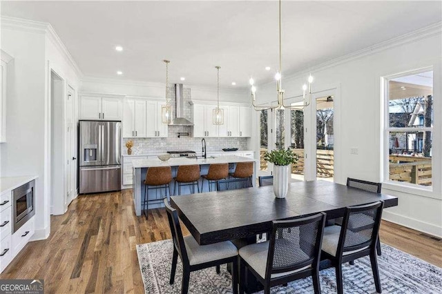 dining space with an inviting chandelier, sink, crown molding, and dark wood-type flooring