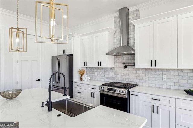 kitchen featuring white cabinetry, stainless steel appliances, decorative light fixtures, and wall chimney range hood