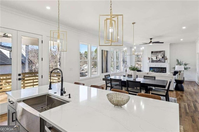 kitchen with hanging light fixtures, ornamental molding, dark wood-type flooring, and sink