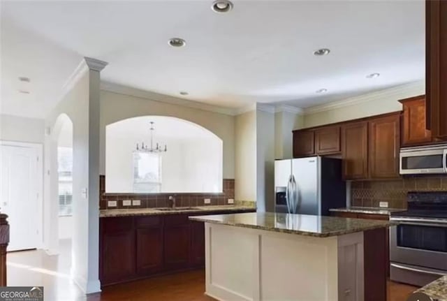 kitchen featuring sink, appliances with stainless steel finishes, dark stone countertops, tasteful backsplash, and a kitchen island