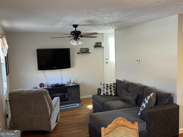 living room with ceiling fan, dark hardwood / wood-style floors, and a textured ceiling