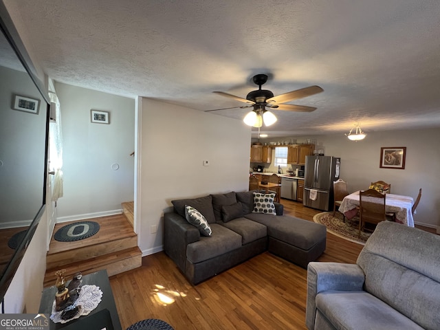 living room featuring ceiling fan, hardwood / wood-style flooring, and a textured ceiling