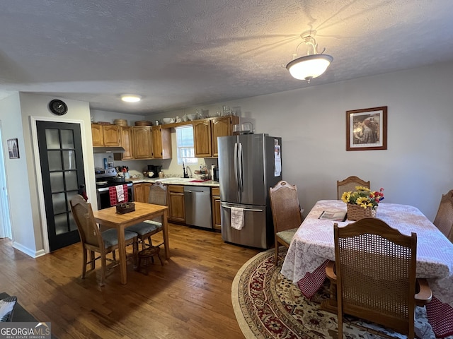 kitchen featuring appliances with stainless steel finishes, sink, a textured ceiling, and dark hardwood / wood-style flooring