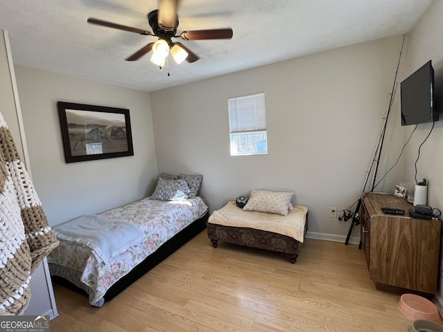 bedroom with ceiling fan, light hardwood / wood-style floors, and a textured ceiling