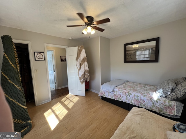 bedroom with ceiling fan, light hardwood / wood-style floors, and a textured ceiling