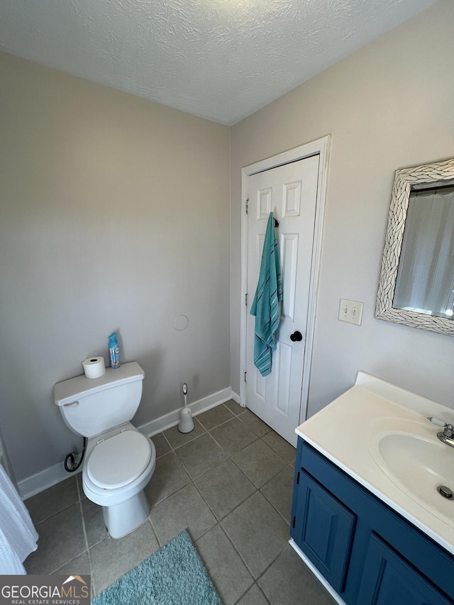 bathroom featuring vanity, toilet, tile patterned flooring, and a textured ceiling