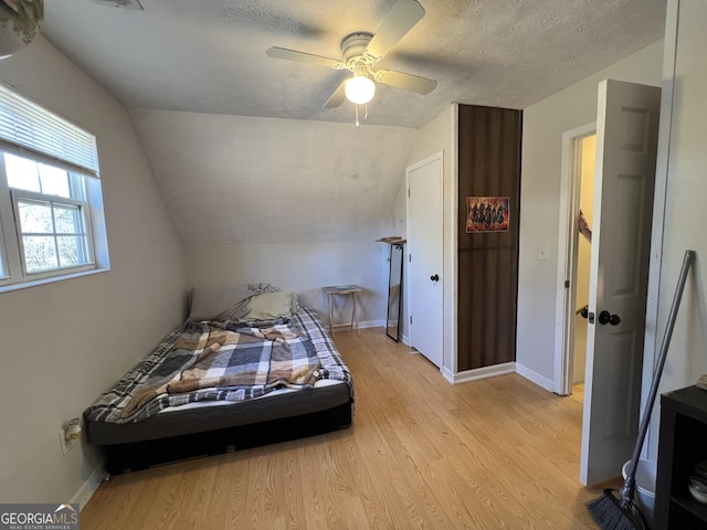 unfurnished bedroom featuring ceiling fan, lofted ceiling, light hardwood / wood-style floors, and a textured ceiling