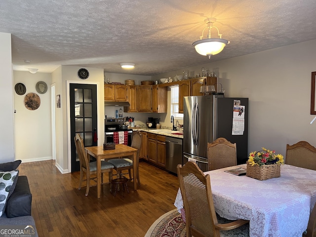 dining area with sink, dark wood-type flooring, and a textured ceiling