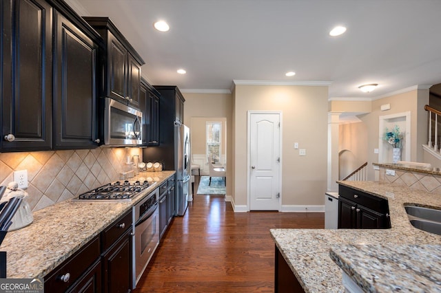 kitchen featuring backsplash, stainless steel appliances, dark hardwood / wood-style floors, light stone counters, and ornamental molding