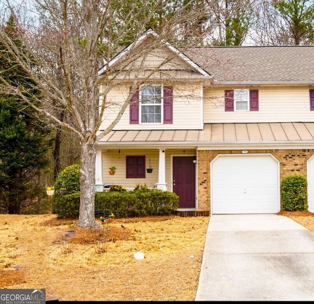 view of front of home with brick siding, a porch, concrete driveway, metal roof, and a standing seam roof