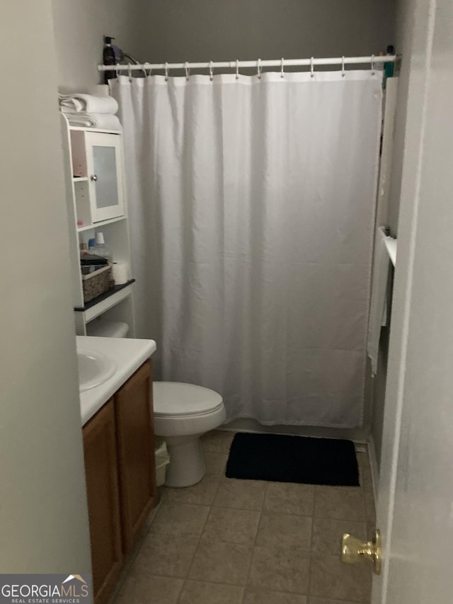 bathroom with vanity, toilet, curtained shower, and tile patterned flooring