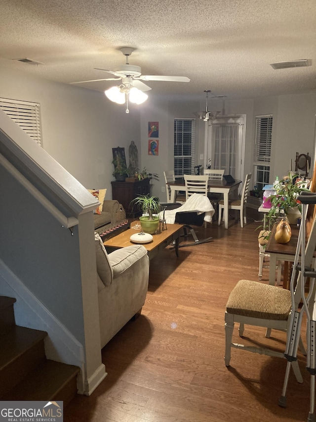 living room with wood-type flooring, a textured ceiling, and ceiling fan