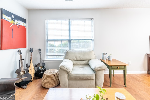 living area featuring visible vents, light wood-style floors, and baseboards