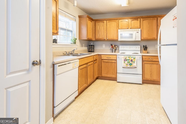 kitchen featuring a sink, white appliances, brown cabinetry, and light countertops