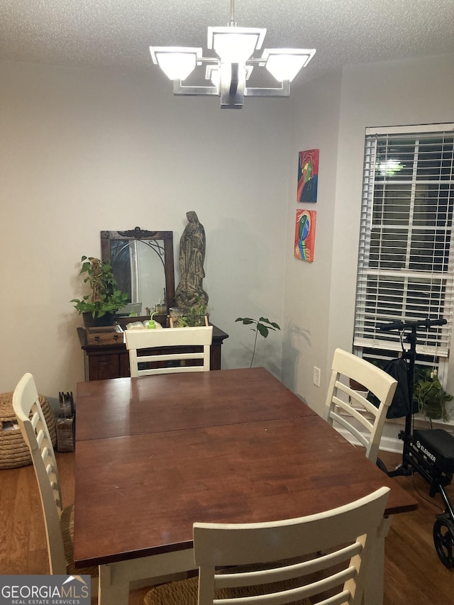 dining room featuring an inviting chandelier, wood-type flooring, and a textured ceiling