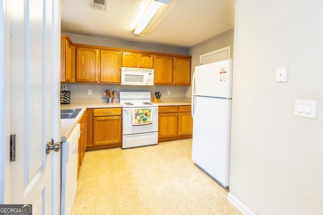 kitchen with visible vents, white appliances, brown cabinets, and light countertops