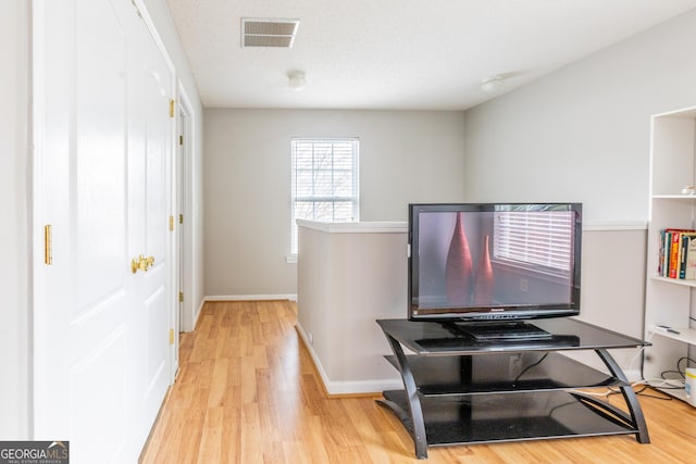 office space featuring visible vents, baseboards, a textured ceiling, and light wood finished floors