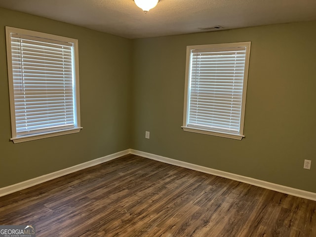 empty room featuring dark hardwood / wood-style flooring and a textured ceiling