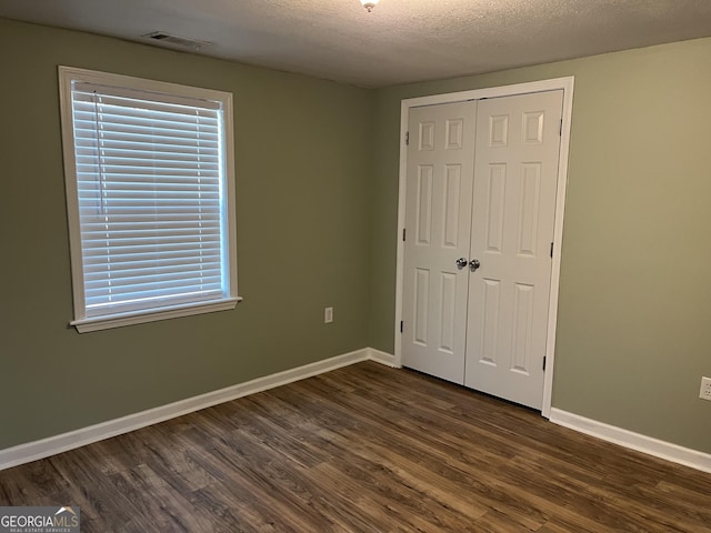 unfurnished bedroom featuring dark hardwood / wood-style floors, a closet, and a textured ceiling