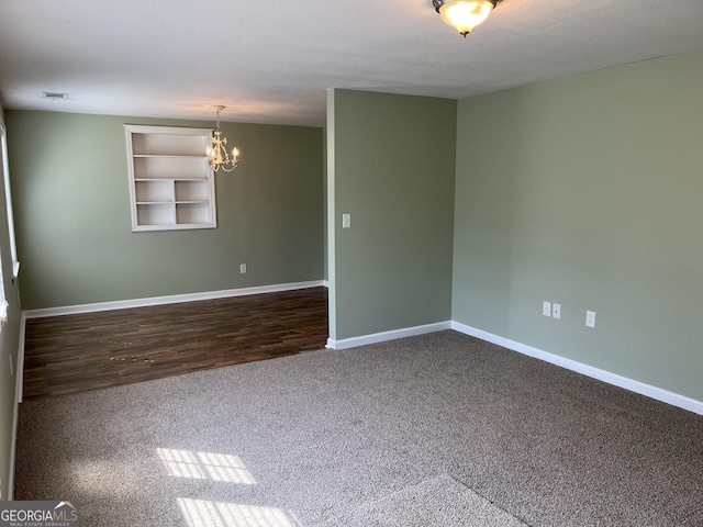 empty room with a chandelier, built in features, and dark colored carpet