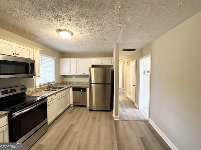 kitchen featuring white cabinetry, sink, light hardwood / wood-style flooring, and appliances with stainless steel finishes