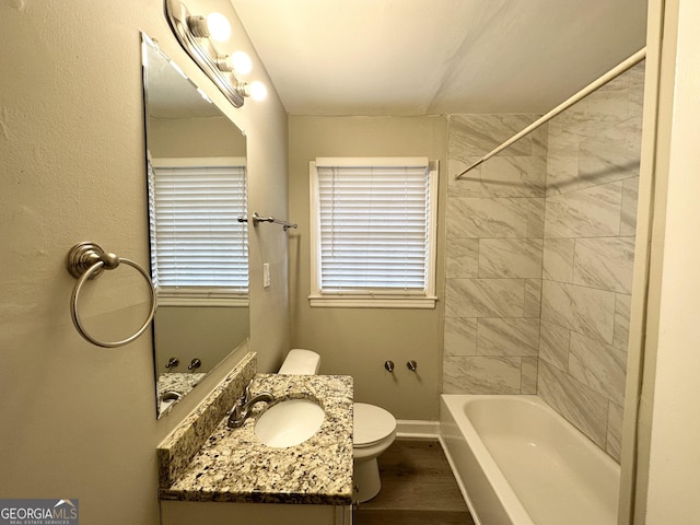 full bathroom with hardwood / wood-style flooring, vanity, tiled shower / bath, and toilet