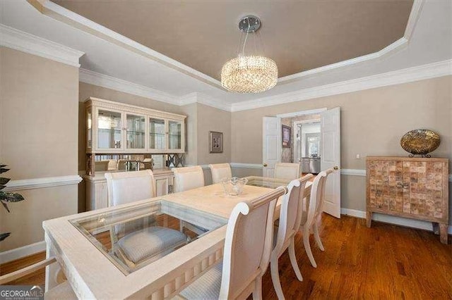 dining space with dark hardwood / wood-style floors, a tray ceiling, crown molding, and a notable chandelier