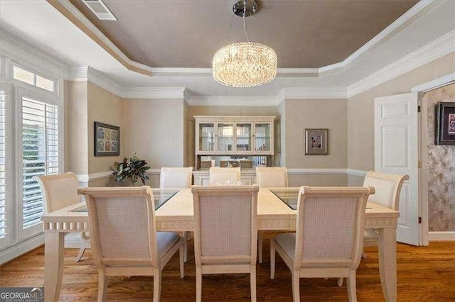 dining room with wood-type flooring, a raised ceiling, and a chandelier